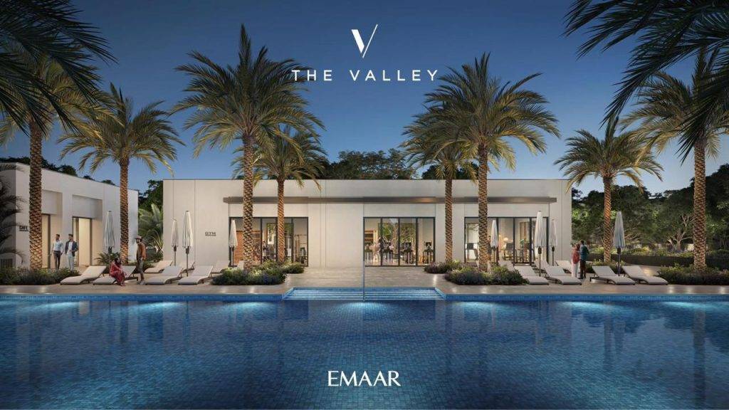 A luxurious residential community pool at The Valley by Emaar, featuring modern architecture and palm trees against a serene evening backdrop.